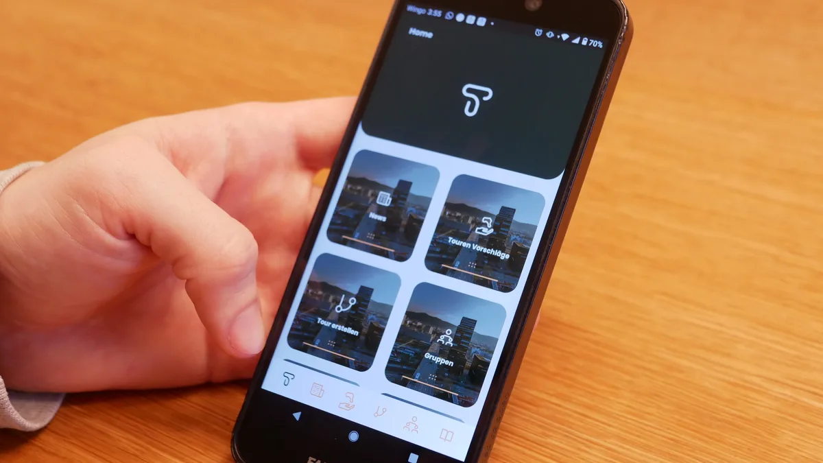 Man sieht eine Hand, die ein iPhone hält und die App The Tours geöffnet hat.